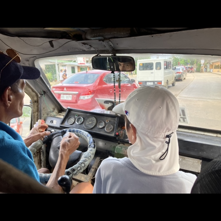 現地の乗り合い車の車内から前方を見た風景と運転手