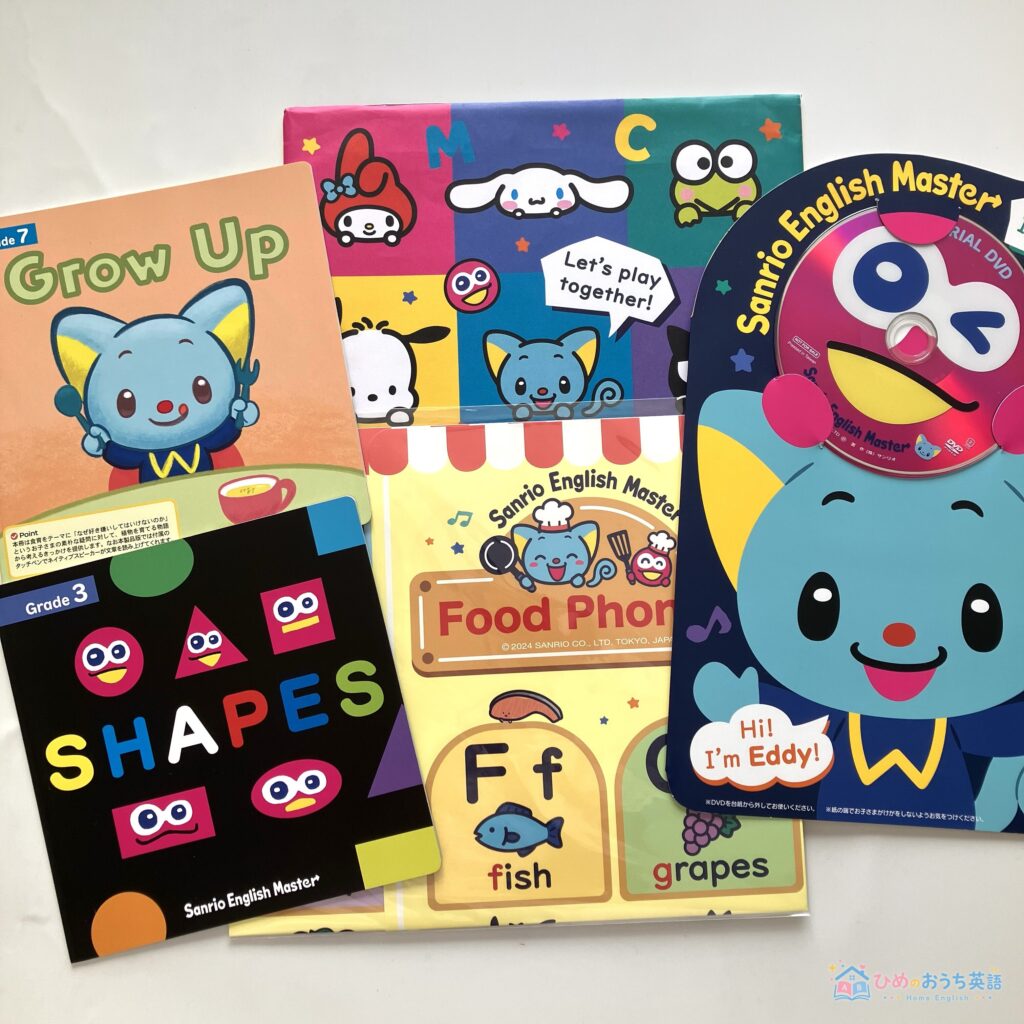 サンリオイングリッシュマスターの無料サンプル教材一式。Grow UpやSHAPESの絵本、Food Phonicsのプリント、体験DVD、メインキャラクターのエディが並んだ実物写真